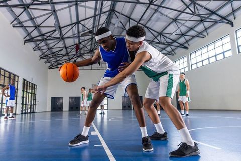 Teen Athletes Dribbling Basketball in Indoor Gym Competition