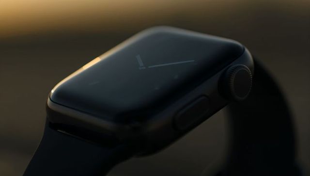 Minimalist black smartwatch macro showing curved glass and digital crown in warm rim light