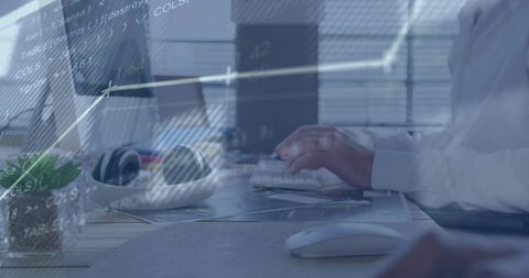 Typing senior man using desktop keyboard at workstation with headphones and data overlay