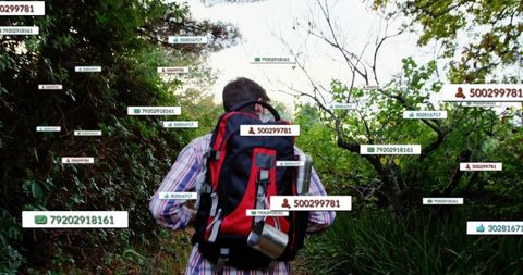 Backpacker walking forest trail wearing red-black pack and thermos with floating id tags