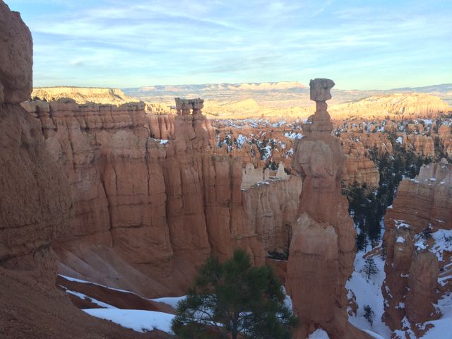 An awe-inspiring view of Bryce Canyon hoodoos illuminated by the gentle morning light. Snow decorates the rocky formations, contributing to a stark yet beautiful contrast. This famous national park in Utah demonstrates impressive geological formations and erosion features, perfect for use in travel brochures, nature documentaries, or promoting outdoor adventures.