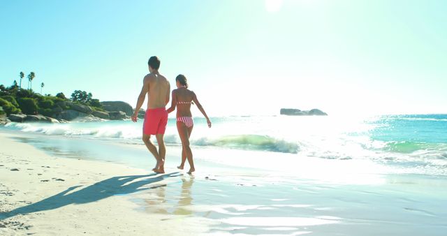 Happy couple holding hands while walking on the beach on a sunny day 4k