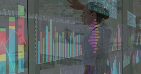 Businesswoman interacting with interactive data dashboards on transparent glass panels