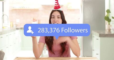 Young woman influencer celebrating 283,376 followers while gesturing in pastel kitchen