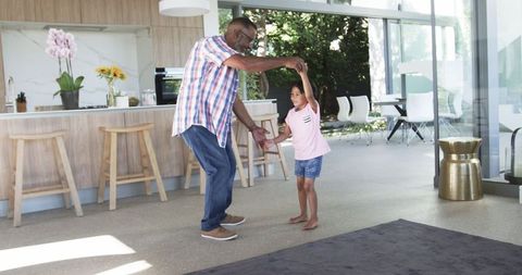 Grandfather and Granddaughter Dancing in Modern Home Living Room
