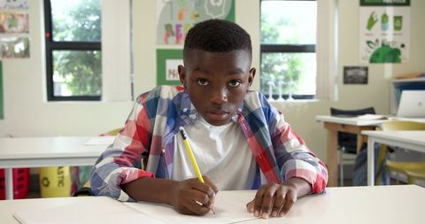 Focused african american boy writing in classroom environment
