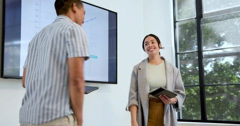 Business duo presenting growth chart and collaborating with tablets in bright office