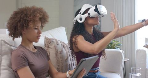 African American friends experiencing virtual reality at home using VR headset and tablet