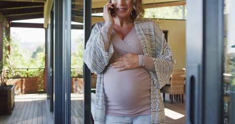 Joyful Pregnant Woman Talking on Phone in Patio Setting