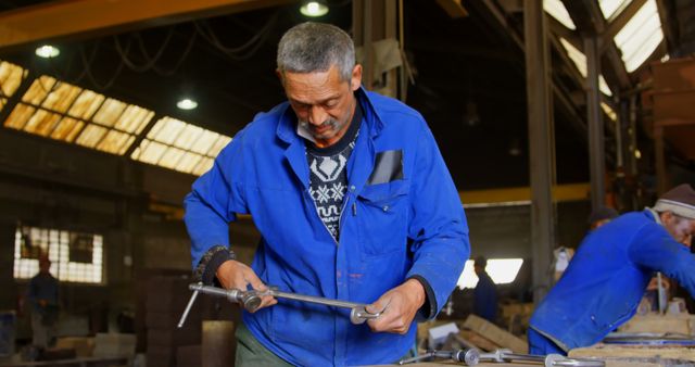 Middle-Aged Male Factory Worker in Blue Uniform Operating Machinery - Download Free Stock Images Pikwizard.com