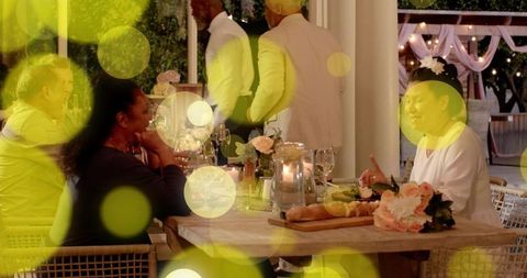 Evening outdoor reception guests gathering and chatting around candlelit wooden dining table