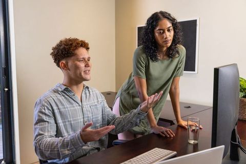 Diverse Colleagues Collaborating Over Computer in Modern Office Environment