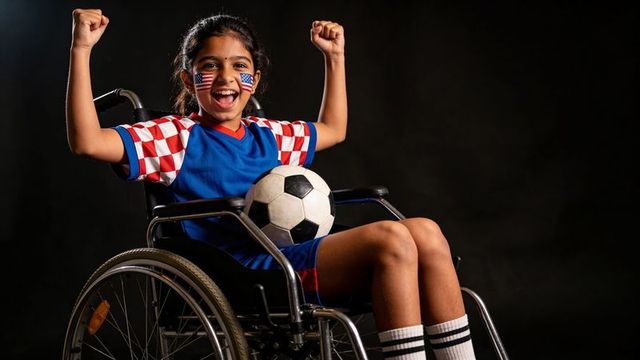 Indian girl in wheelchair celebrating with soccer ball and american flag face paint