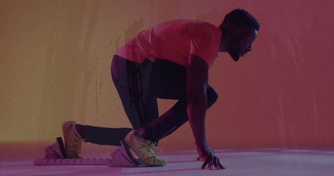 Athlete in Dynamic Start Position with Spiked Shoes in Modern Studio Setting