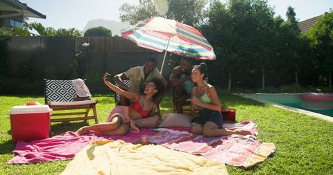 Diverse Friends Enjoying Backyard Poolside Selfie Under Umbrella