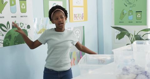 Young african girl presenting and sorting recycling in classroom during sustainability workshop