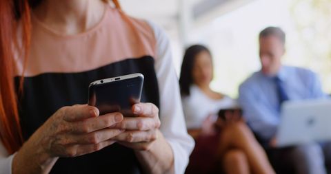Women and men using digital devices in modern office