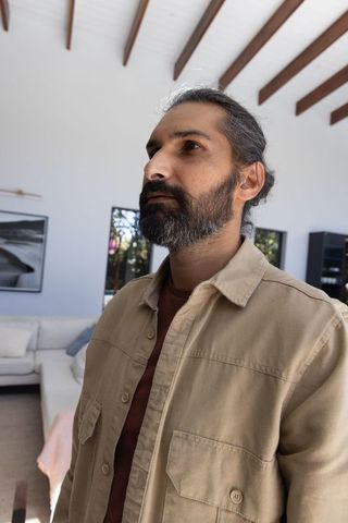 Pensive indian man reflecting in minimalist modern living room