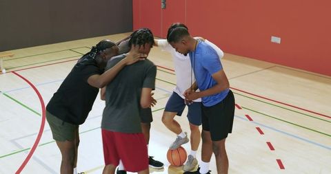 Youth basketball team huddling with coach blowing whistle for pep talk and teamwork