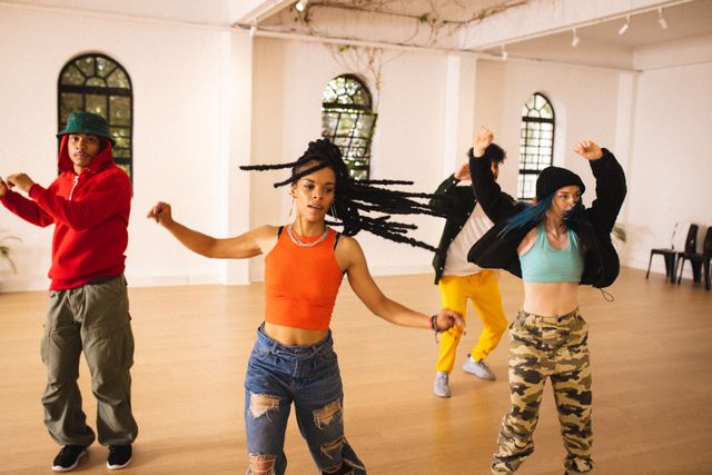 Energetic group of dancers practicing together in a brightly lit dance studio. Ideal for use in content about lifestyle, teamwork, fitness routines, and creative expressions. Perfect for dance-related blogs, fitness websites, and social media posts highlighting unity and diversity.