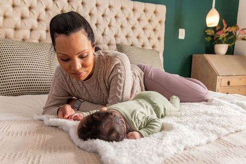 African american mother bonding with newborn on cozy bed, nurturing tender moment