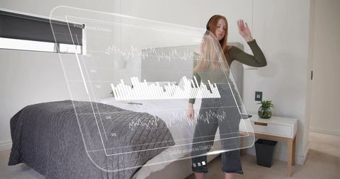 Woman wearing headset interacting with holographic data and graphs in modern bedroom