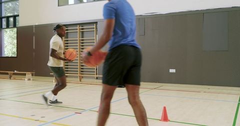 African american athletes dribbling basketball during agility drill, training session