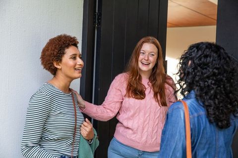 Diverse Female Friends Smiling and Conversing at Home Entrance