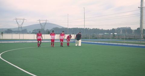 Hockey players outdoors carrying goalie pads on turf