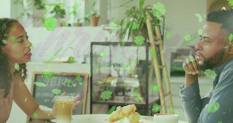 Couple having relaxed coffee conversation at cafe with iced latte, croissants and greenery