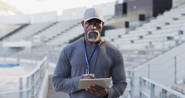 African american male coach looking at camera and smiling. professional runner training at sports stadium.