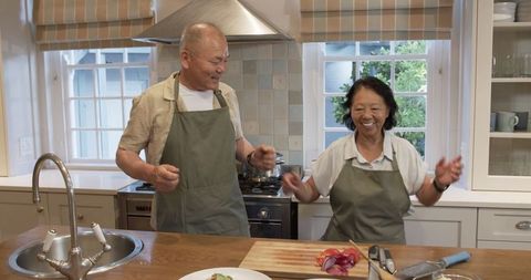 Senior couple cooking together at home laughing