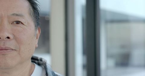 Mature Asian Man in Modern Lobby with Glass Panels