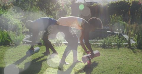 African American Couple Rolling Yoga Mats in Sunny Garden