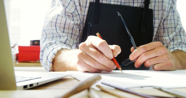 Male Designer Working at Desk Holding Glasses and Pencil - Download Free Stock Images Pikwizard.com