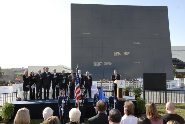 KENNEDY SPACE CENTER, FLA. --  Guests and attendees salute the U.S. flag during a ceremony at the KSC Visitor Complex held in remembrance of the astronauts lost in the Apollo 1 fire: Virgil "Gus" Grissom, Edward H. White II and Roger B. Chaffee.  Among those gathered on stage are (from left) Faith Johnson, daughter of Theodore Freeman and Martha Chaffee, daughter of Roger Chaffee, Associate Administrator for Space Operations William Gerstenmaier and KSC Director Bill Parsons,  plus former astronaut John Young and Lowell Grissom, brother of Gus Grissom (far right). At the podium is Stephen Feldman, president of the Astronauts Memorial Foundation.  Behind the stage is the Space Mirror Memorial, designated as a national memorial by Congress and President George Bush in 1991 to honor fallen astronauts.  Their names are emblazoned on the monument’s 42-½-foot-high by 50-foot-wide black granite surface as if to be projected into the heavens.  Photo credit:NASA/Kim Shiflett