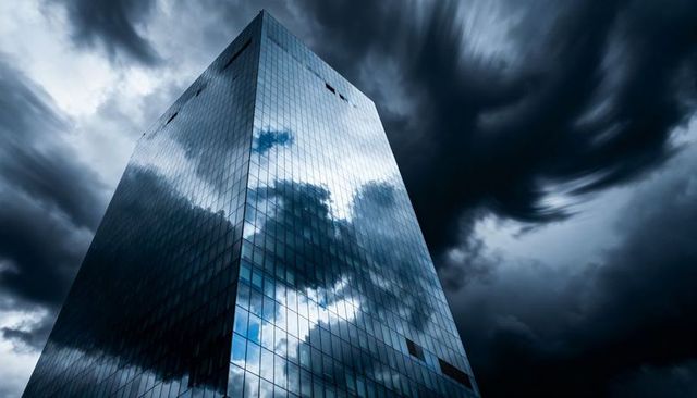 Glass Skyscraper Reflecting Dark Storm Clouds from Low Angle, Dramatic Corporate Tower