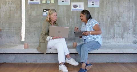 Diverse Coworkers Collaborating with Laptop and Tablet in Workspace