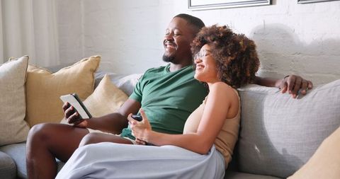Couple Relaxing Together With Tablet and Remote on Cozy Sofa