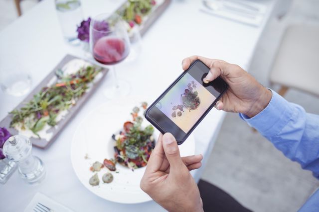 Man taking picture of food from mobile phone in restaurant