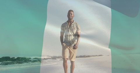 Man walking on sunny beach with translucent flag double exposure