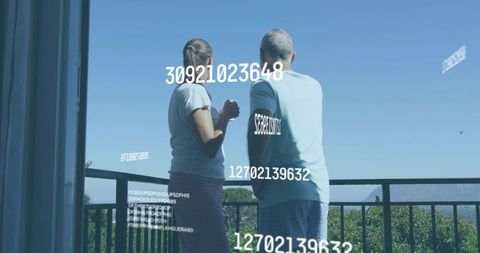 Mature couple standing on balcony overlooking valley with numeric data overlay