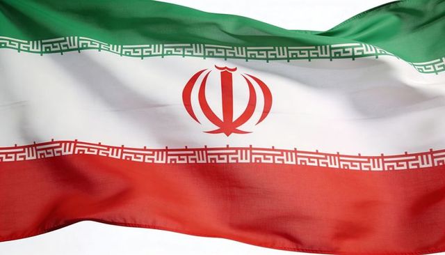 Waving iranian flag close-up with red emblem, kufic script and translucent fabric folds