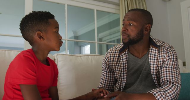 African american dad talking to his son while holding his hand at home - Download Free Stock Photos Pikwizard.com