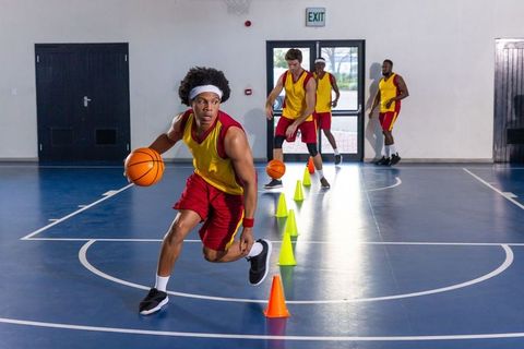 Basketball players practicing dribbling skills in indoor court