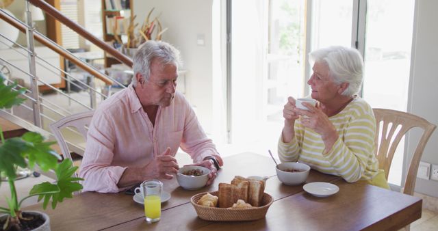 Senior caucasian couple talking to each other having breakfast together at home. retirement senior couple lifestyle living