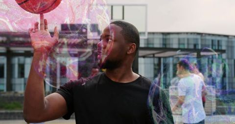 Urban athlete spinning basketball on fingertip with colorful swirl overlays at rooftop plaza