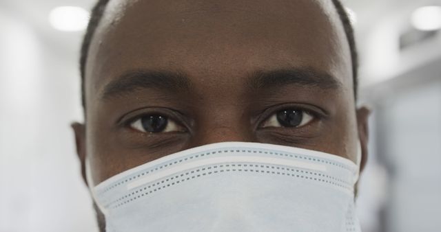 This close-up image depicts a healthcare professional wearing a protective mask, highlighting the eyes and mask. Ideal for content related to healthcare, safety, medical professionals, pandemic response, hospitals, and clinics.