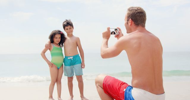 Father taking picture of his children on the beach 