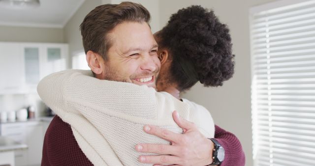 Image of happy diverse couple hugging in kitchen. Love, relationship and spending quality time together at home.